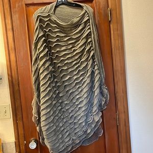 Long frilly knit tiered acrylic poncho. Taupe color. Slightly asymmetrical.